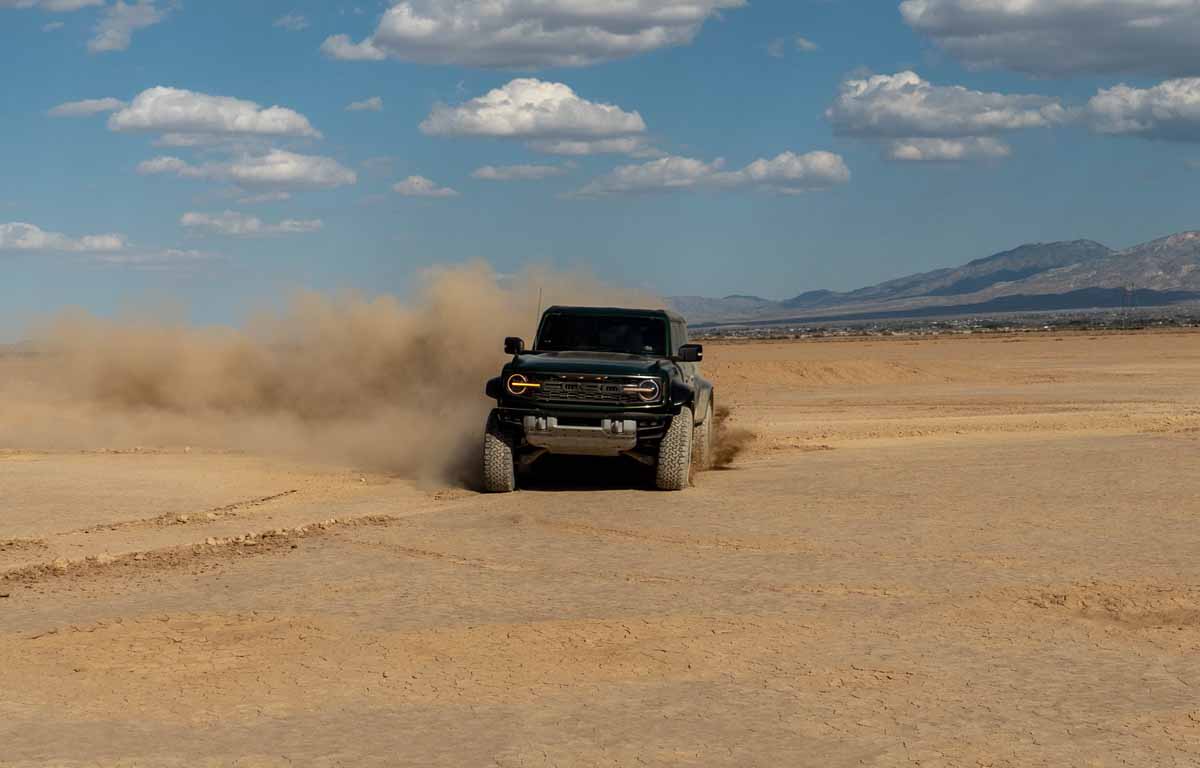 Green 2022 Ford Bronco Raptor driving in dirt on a dry lake bed in southern california