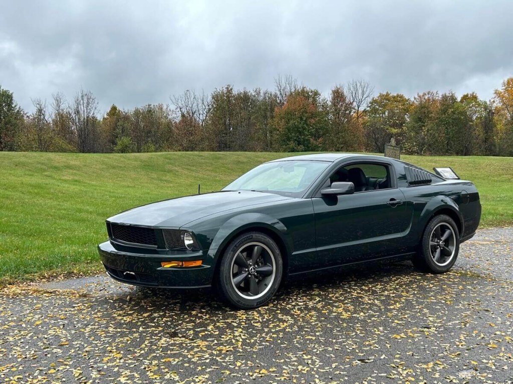 A 2008 Ford Mustang Bullitt in Dark Highland Green parks in a large lot.