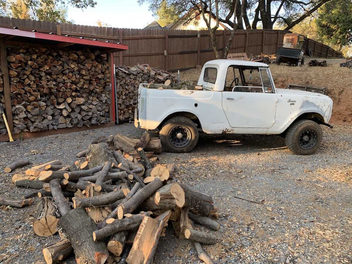 International Harvester Scout parked in front of some fire wood.