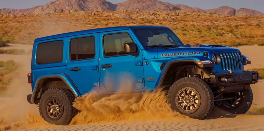 A blue 2023 Jeep Wrangler Rubicon 392 SUV is driving in sand. 
