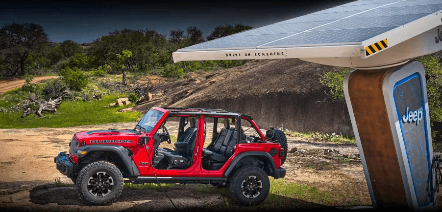 A red Jeep Wrangler Rubicon 4xe plug-in hybrid (PHEV) model near a solar-powered EV charging station