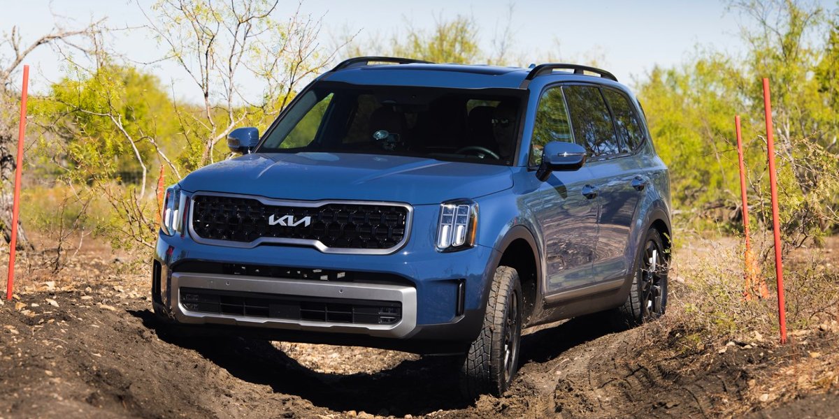 A blue 2024 Kia Telluride is driving off-road.