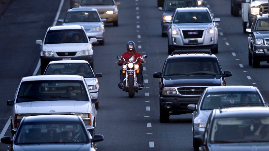 This motorcycle is lane splitting between slow-moving traffic in a state where it is legal because the local laws define and allow it.