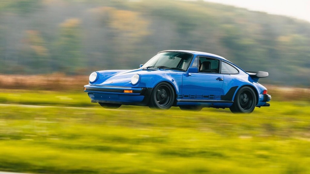 A Porsche 911 930 blasts across a country road.