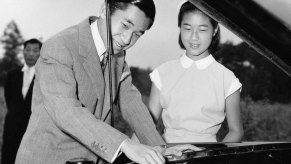 Prince Takako (R) watching her brother Prince Akihito (L) working on the engine of his 1954 Prince Motor Company car