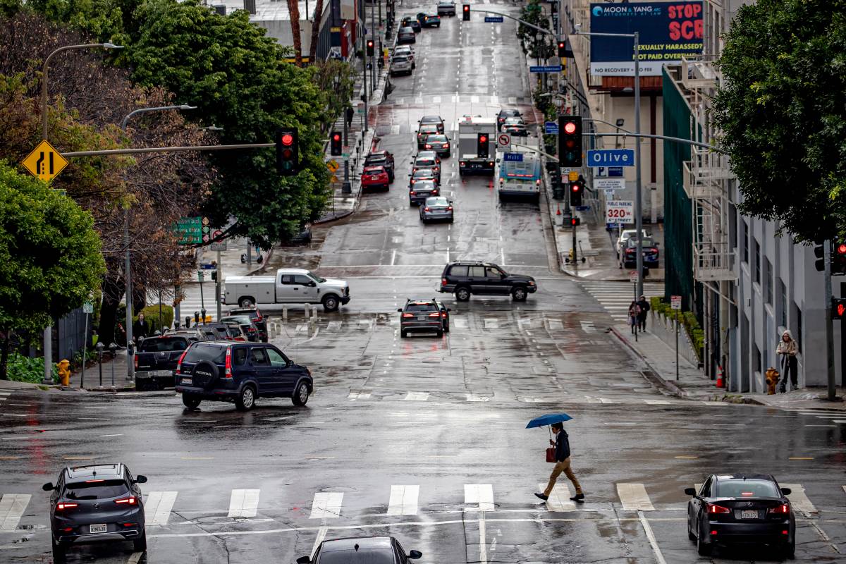 A rainy city street with cars driving safely up and down it