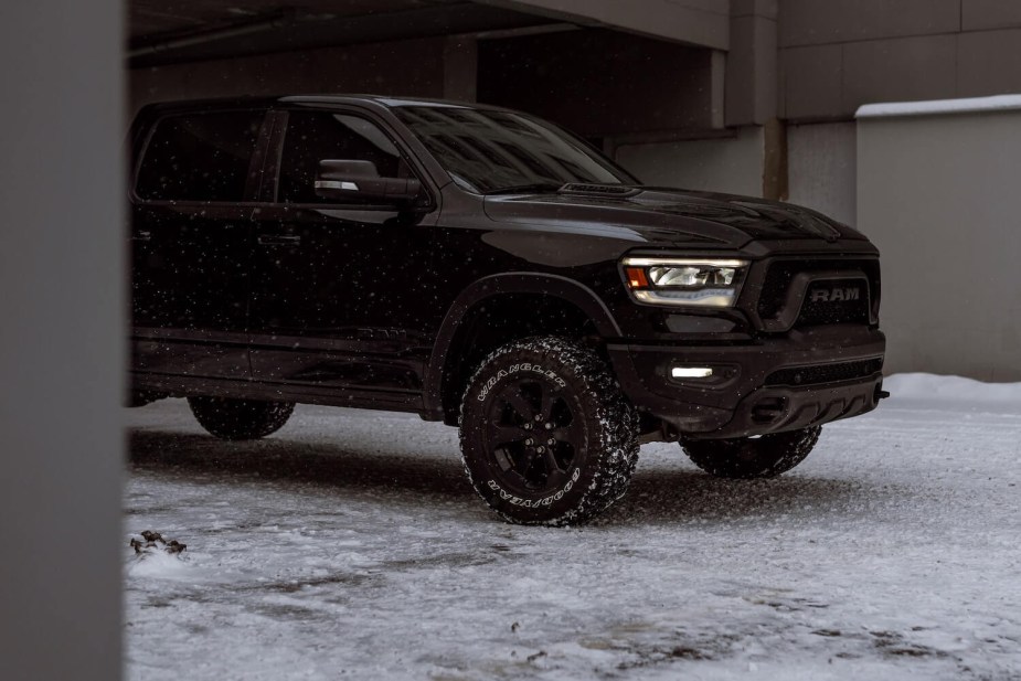 A black Ram truck parked in a carport, snow beneath its tires.