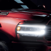 A 2023 Ram 2500 heavy-duty pickup truck model with a red paint color option and its headlights illuminated
