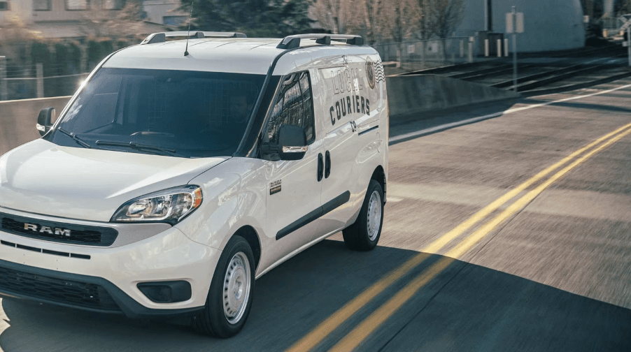 A 2022 Ram ProMaster City panel van/commercial vehicle model in white driving past concrete guard rails