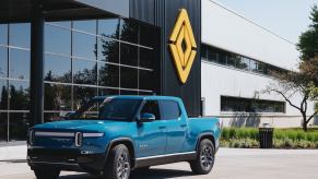 A blue electric pickup truck parked in front of the Rivian factory.