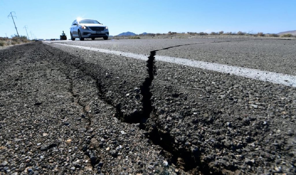 A deep crack in road asphalt awaits a sealant 'tar snake' fix.