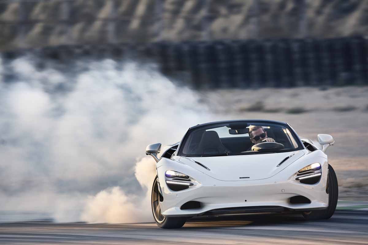 white McLaren 750S Spider drifting in a cloud of tire smoke with the top down