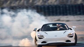 white McLaren 750S Spider drifting in a cloud of tire smoke with the top down