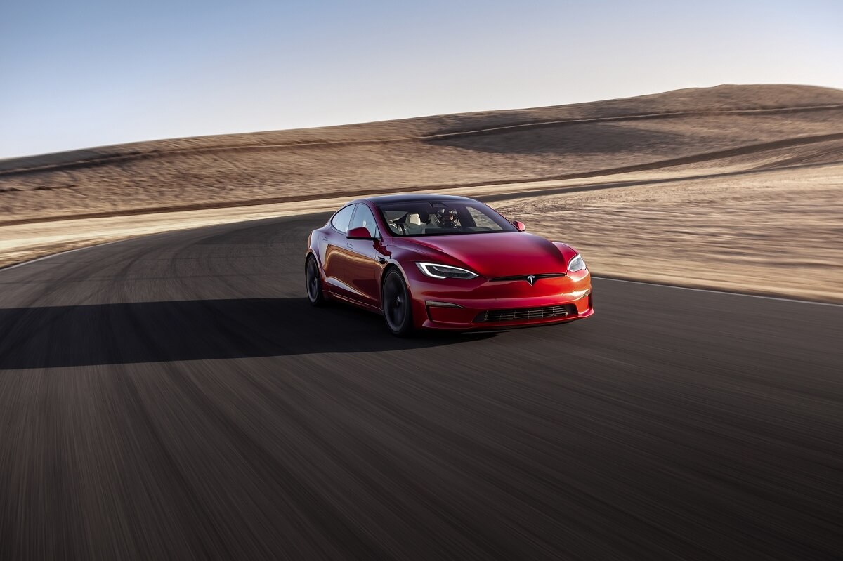 A red, fully loaded 2023 Tesla Model S corners on a track.