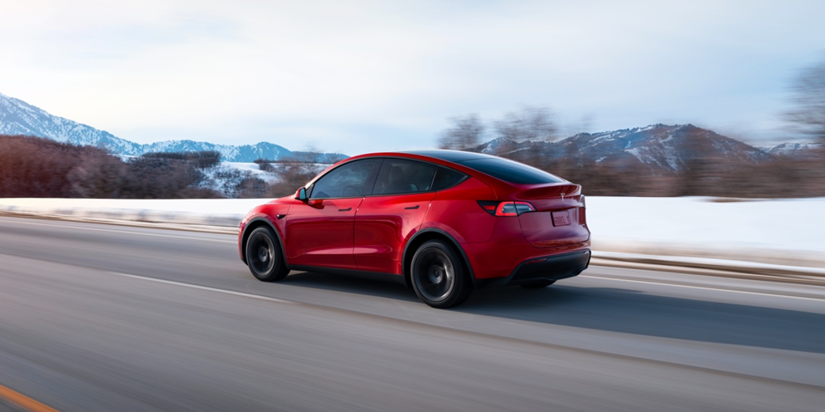 A red 2023 Tesla Model Y is driving on the road.