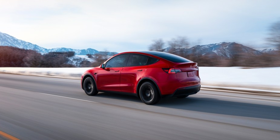 A red 2023 Tesla Model Y is driving on the road. 