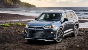 A blue 2024 Toyota Grand Highlander is parked near water.