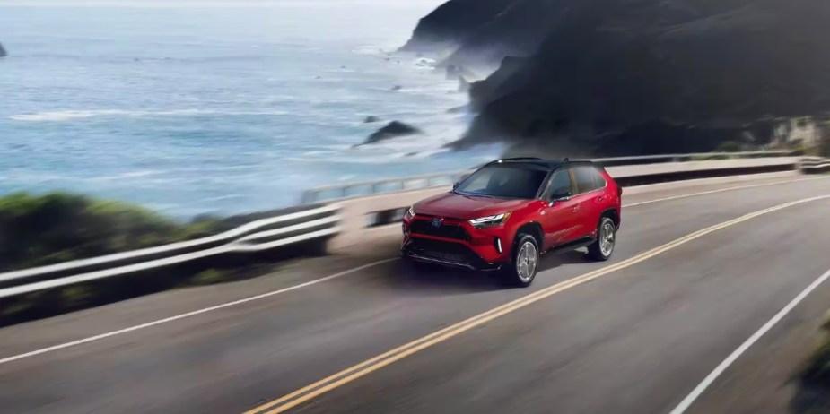 A red 2023 Toyota RAV4 Prime small plug-in hybrid SUV is driving.