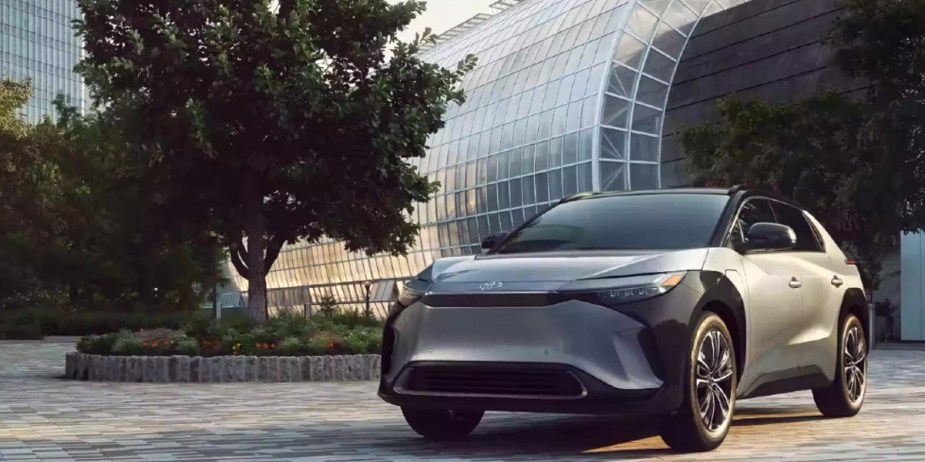 A gray 2023 Toyota bZ4X small electric SUV is parked outdoors near a tree. 