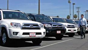 A salesmen walks by a row of used Toyota 4Runner SUVs.