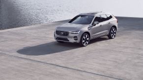 A 2023 Volvo XC60 Recharge plug-in hybrid (PHEV) compact luxury SUV model parked on a concrete dock by water