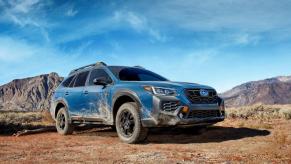 A 2024 Subaru Outback midsize SUV/station wagon model in a desert with its body caked in dirt, dust, and grime