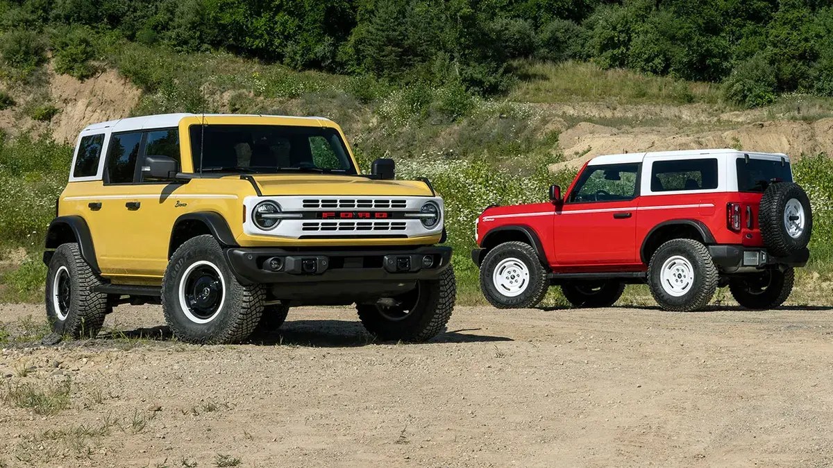 A yellow and a red Ford Bronco parked on display.