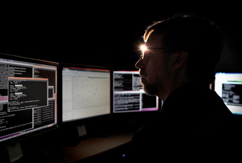 A man studies cybersecurity on multiple security screens.