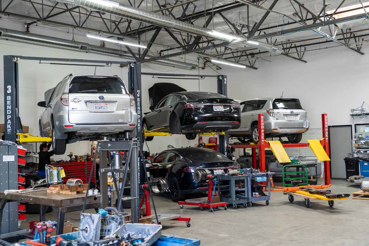 A photo inside of the QC Charge EV repair center, with several Tesla models being repaired