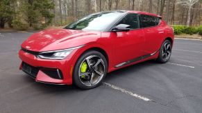 A red 2023 Kia EV6 GT compact electric SUV with neon yellow brake calipers parked in a forest parking lot