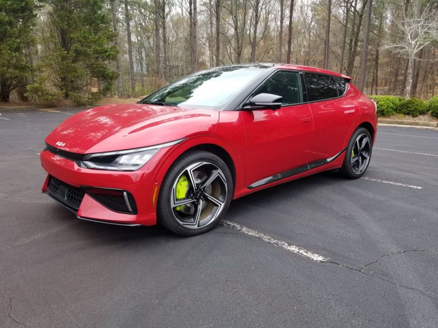 A red 2023 Kia EV6 GT compact electric SUV with neon yellow brake calipers parked in a forest parking lot