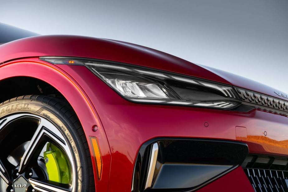 A closeup shot of a 2023 Kia EV6 GT electric compact SUV's headlight, grille, and wheel design