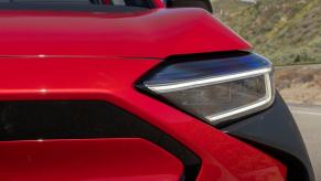 A 2023 Subaru Solterra electric compact SUV model shot of an illuminated headlight near the grille and cladding