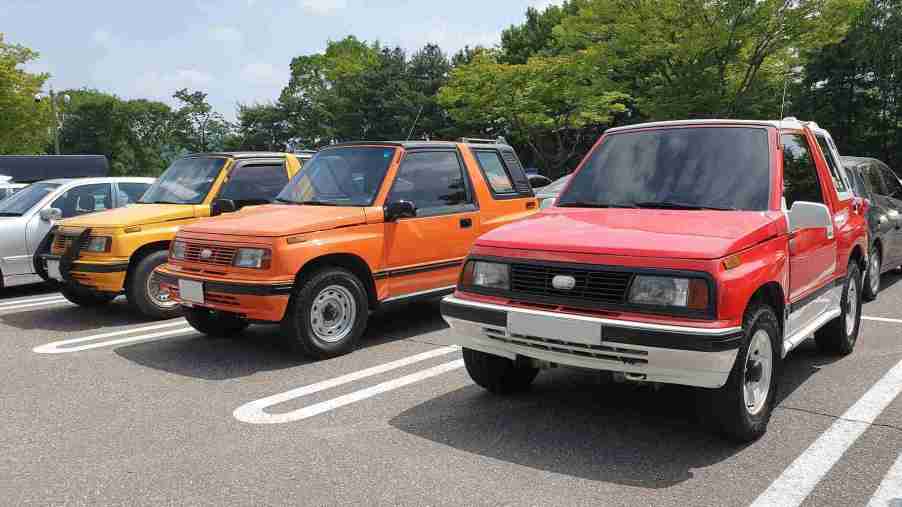 Three Geo Trackers parked next to each other all in different colors; yellow, orange, and red.