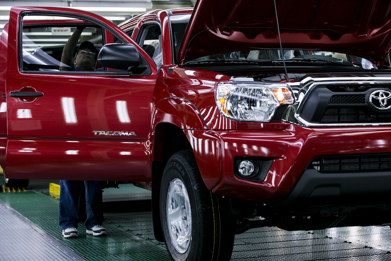 A worker checks over a used Toyota Tacoma in the final production line before driving the truck out of the factory at the Toyota Motor Manufacturing Texas