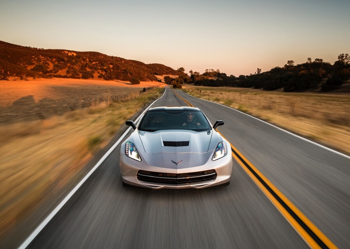 A silver C7 Chevrolet Corvette Stingray drives through the desert.
