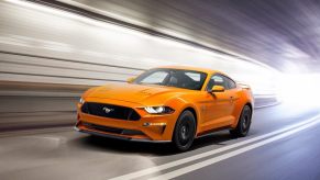 An orange 2018 Ford Mustang GT cruises through a tunnel.