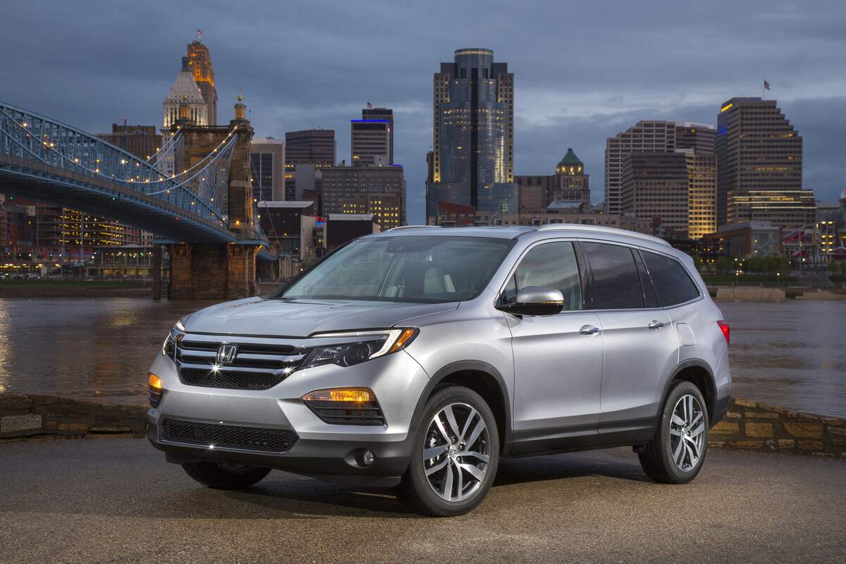 A silver 2018 Honda Pilot Elite parked overlooking a river, bridge, and high-rises