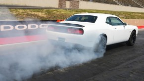A white Dodge Challenger 1320 muscle car does a burnout.