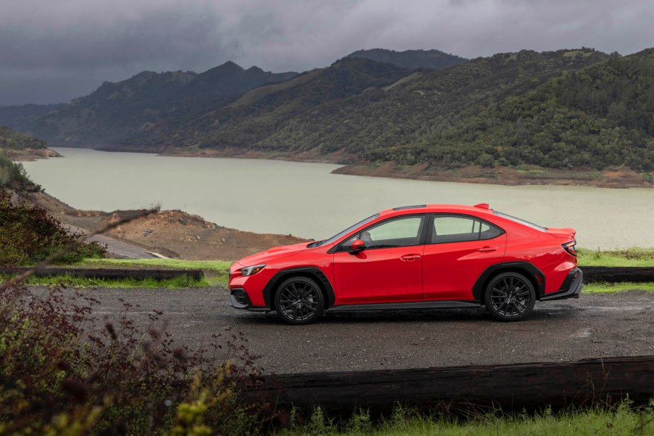 A red 2022 Subaru WRX parked in front of a lake. The Subaru WRX price is higher than it should be to be competitive in sales.