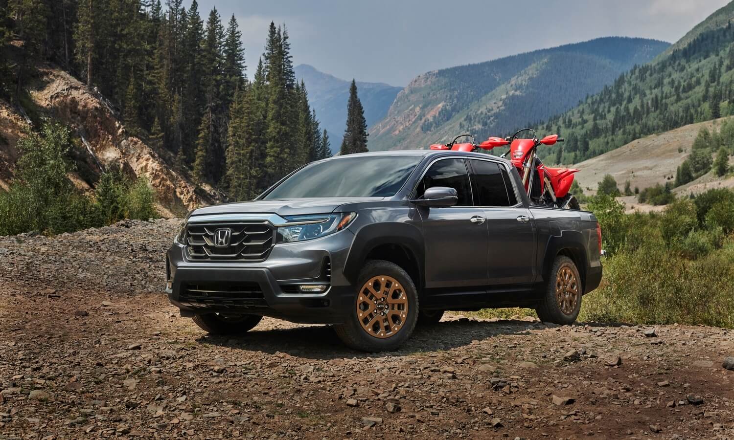 The 2023 Honda Ridgeline off-roading while carrying dirt bikes in the bed