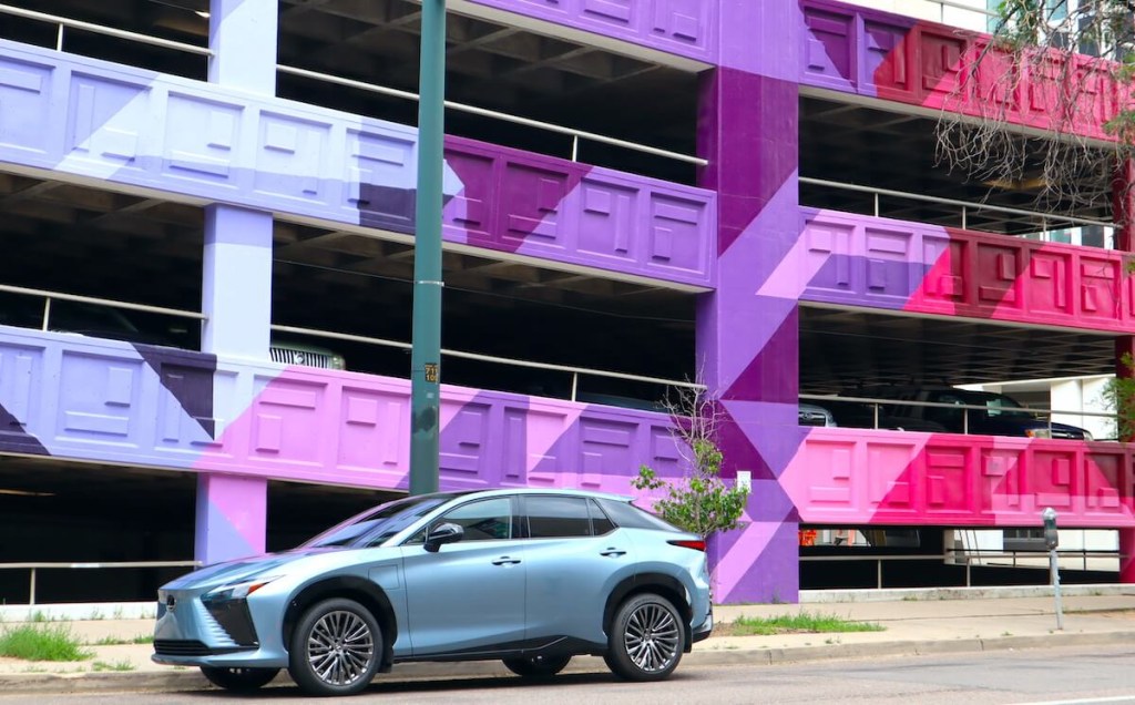The 2023 Lexus RZ 450e in front of a colorful parking structure.