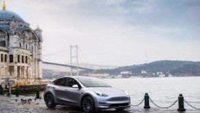 A gray 2023 Tesla Model Y small electric SUV is parked by the water.