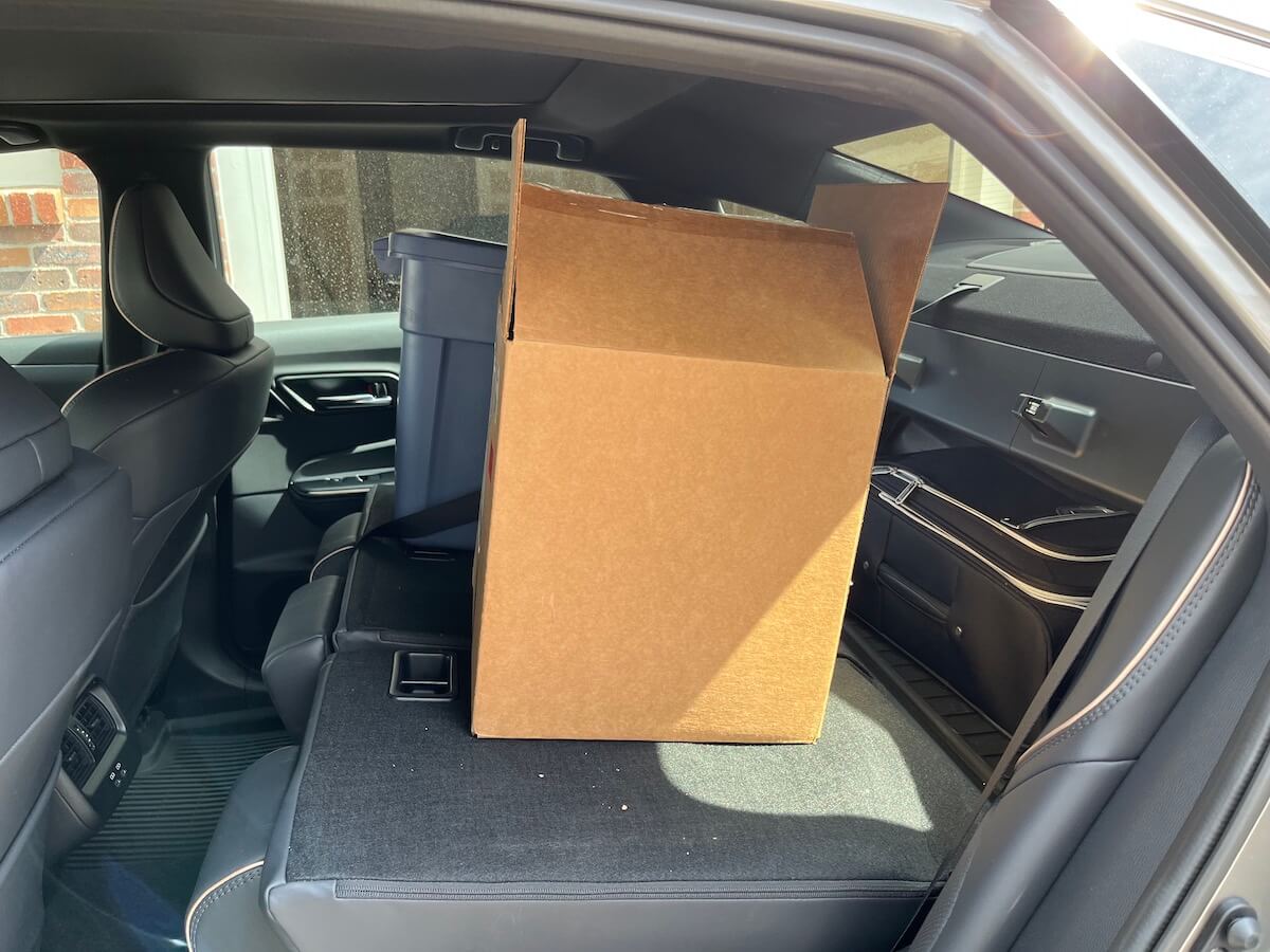 2023 Toyota Crown full-size sedan with the rear seat folded down and a box and blue bin sitting on top.