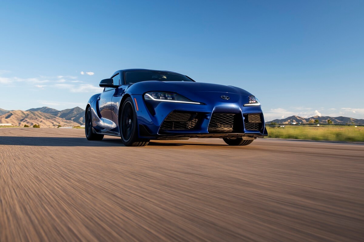 A 2023 Toyota GR Supra 3.0 drives across an open track surface. 