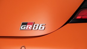 An orange 2023 Toyota GR86 flashes its rear badge.