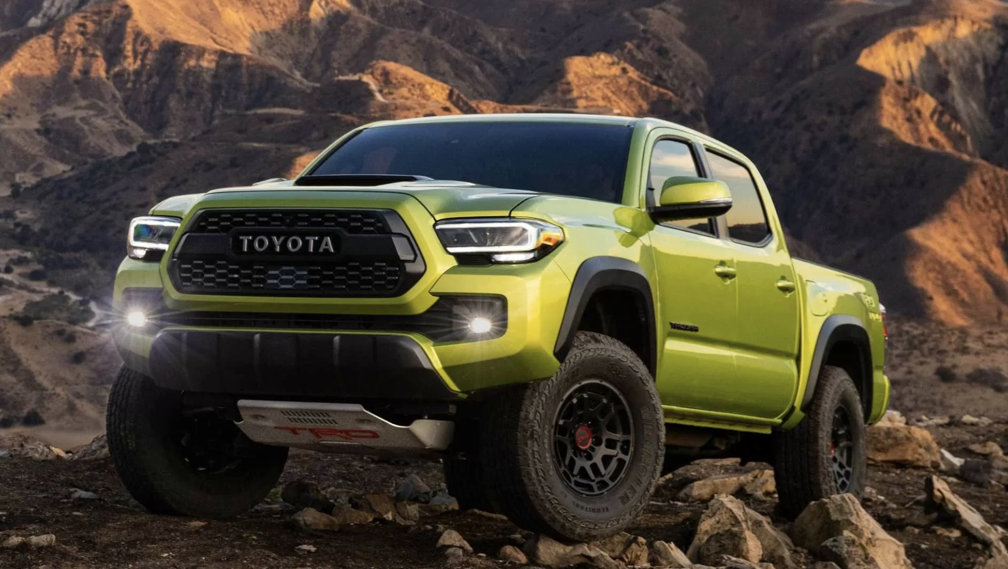 A green 2023 Toyota Tacoma tackling a rocky off-roading trail