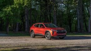 A red new Chevy Trax model parked near a forest is one of the cheapest cars