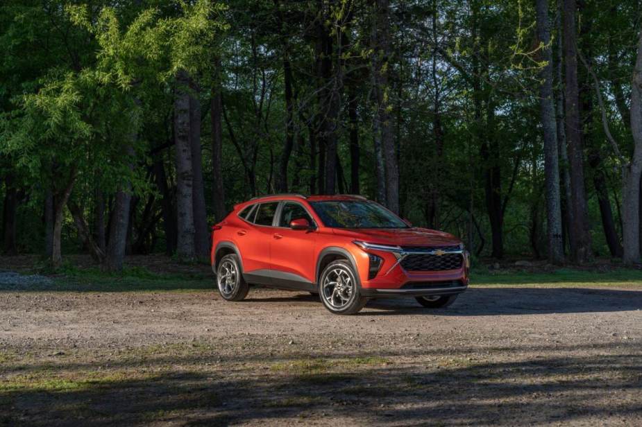 A red new Chevy Trax model parked near a forest is one of the cheapest cars