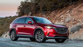 Red 2023 Mazda CX-90 SUV with hill in background